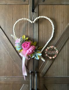 a heart shaped door with flowers and pearls attached to the handle, in front of a barn door