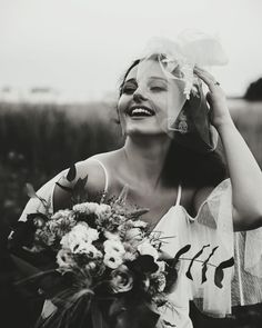 black and white photograph of a woman in a dress holding a bouquet with her eyes closed