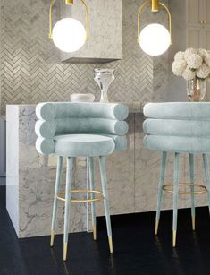 three light blue stools in front of a marble bar with flowers on the counter