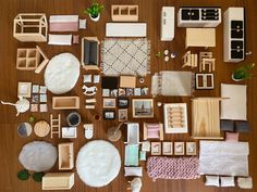 a collection of dollhouse furniture and accessories on a wooden table with white rugs