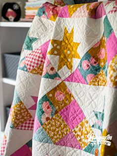 a colorful quilt is hanging up on a chair in front of a bookshelf