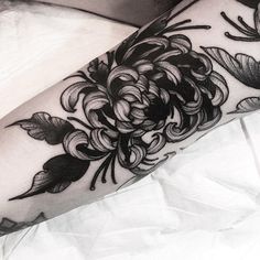 a black and white photo of a woman's leg with flowers on it