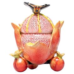 a red and yellow vase sitting on top of some fruit