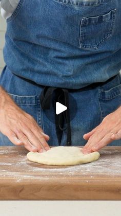 a person is kneading dough on top of a wooden table with their hands