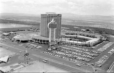 an old black and white photo of a parking lot in front of a large building