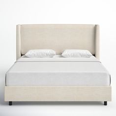 a bed with white sheets and pillows on it