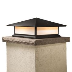 a light that is on top of a wall next to a lamp post with a black roof