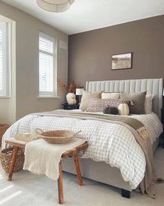 a bedroom with a large bed and white pillows on it's headboard, along with two wicker stools