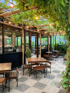 an outdoor dining area with wooden tables and benches, surrounded by greenery on the walls