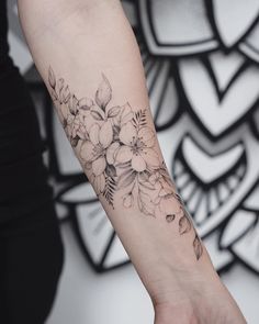 a woman's arm with flowers and leaves on her left wrist, in front of a black and white background