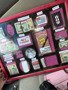 a pink and black framed display with lots of money