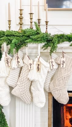 stockings hanging from a mantel decorated with evergreen needles and personalized tags for the couple's names