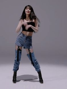 a woman in black top and blue jeans posing for a photo with her arms spread out