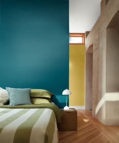 a bed sitting next to a blue wall in a room with wooden floors and walls