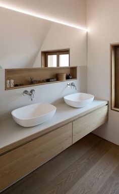 two white bowls are sitting on the counter in this modern bathroom with wood flooring