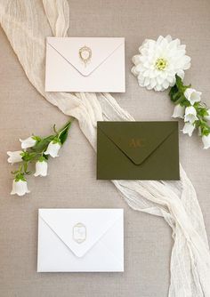 the wedding stationery is laid out with white flowers and green envelopes