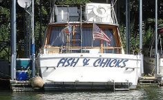 a boat is docked at the dock with flags on it's mast and another boat in the background