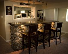 the bar is made out of stone and has four chairs around it, along with two stools