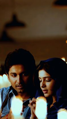 a man and woman sitting next to each other in front of some lit up candles