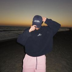 a man standing on top of a sandy beach next to the ocean at sunset or dawn