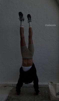 a person doing a handstand in front of a wall with their feet up