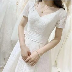 a woman wearing a white dress standing in front of wedding gowns