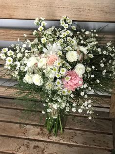 a bouquet of flowers sitting on top of a wooden bench