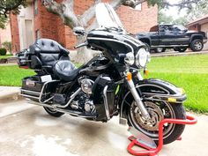 a black motorcycle parked in front of a house on a sidewalk next to a tree