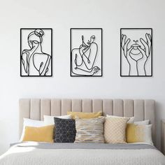 a bedroom with three framed artwork above the bed