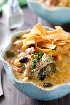 a bowl filled with soup and chips on top of a wooden table