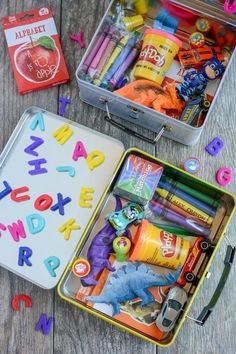 two tins filled with school supplies on top of a wooden table