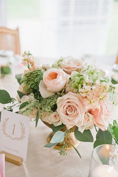 a vase filled with lots of pink flowers on top of a table next to candles