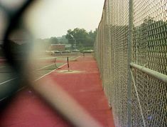 a tennis court through a chain link fence