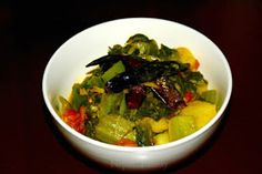 a white bowl filled with vegetables on top of a wooden table