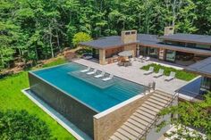 an aerial view of a house with a swimming pool in the foreground, surrounded by trees