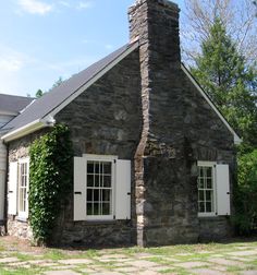 an old stone house with white shutters and ivy growing up the side of it