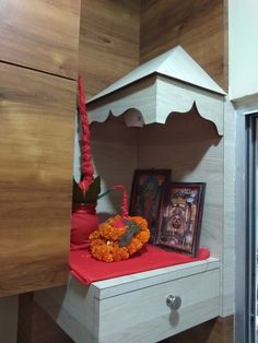 a small shrine with flowers and pictures on the shelf next to it, in front of a wooden paneled wall