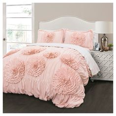 a bed with pink comforter and pillows in a room