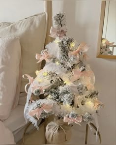 a white christmas tree with pink bows and lights