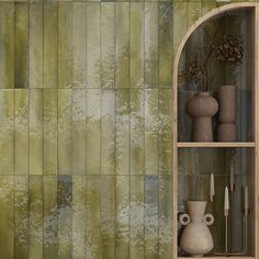 a shelf with vases and other decorative items on it in front of a green tiled wall