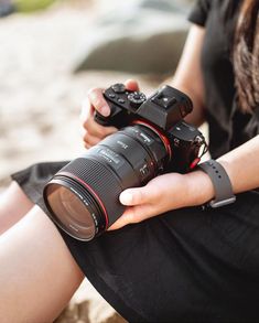 a woman sitting on the ground holding a camera