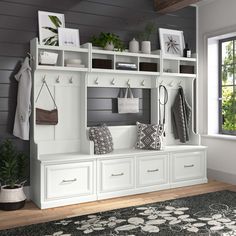 a large white bench with some drawers and hooks on it's sides, in front of a window