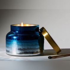 a candle that is sitting next to a glass container with a match in it's mouth