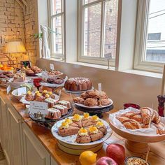 an assortment of pastries and desserts on display in a room with large windows