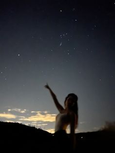 a woman standing on top of a hill under a sky filled with stars