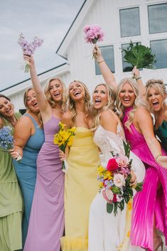 a group of women standing next to each other holding flowers and bouquets in their hands