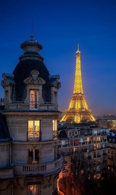 the eiffel tower lit up at night in paris, with buildings surrounding it