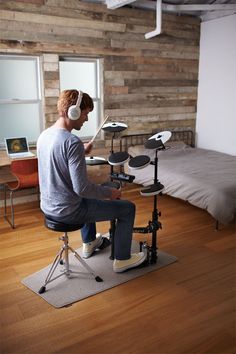 a man sitting on top of a chair in front of a drum set and headphones