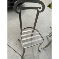 a metal chair sitting on top of a sidewalk