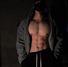 a shirtless man with no shirt standing in the dark wearing a hoodie and sweatpants